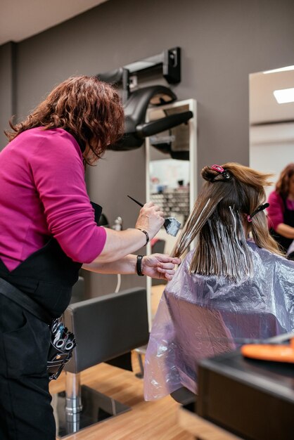 Peluquero teñir el cabello de una mujer