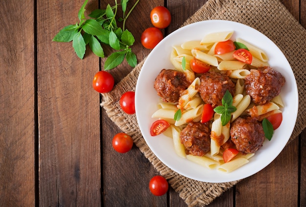 Penne pasta con albóndigas en salsa de tomate en un tazón blanco