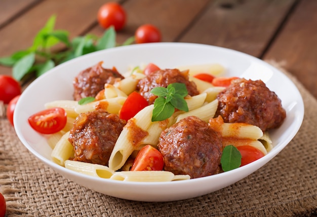 Penne pasta con albóndigas en salsa de tomate en un tazón blanco