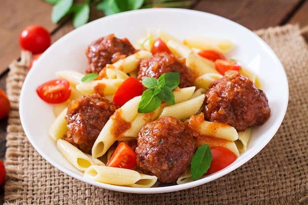 Penne pasta con albóndigas en salsa de tomate en un tazón blanco