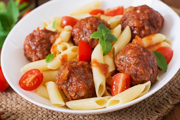 Penne pasta con albóndigas en salsa de tomate en un tazón blanco