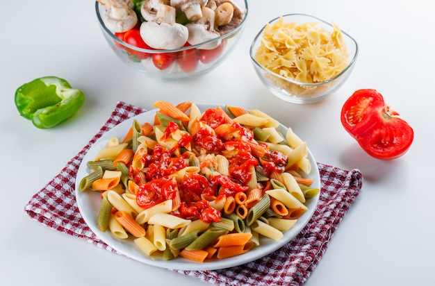 Penne pasta con champiñones, tomate, salsa, pimienta, pasta cruda en un plato