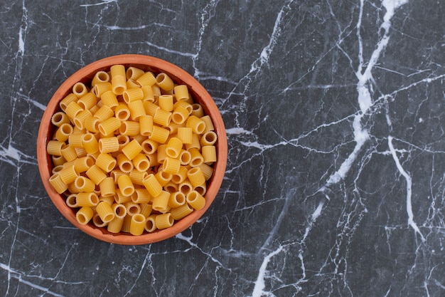 Foto gratuita penne de pasta cruda vista superior en tazón de fuente de madera.