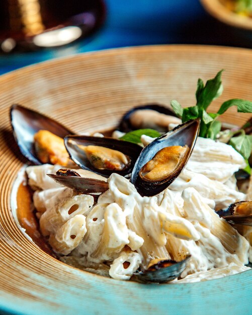 Penne pasta con mejillones vista lateral a la menta