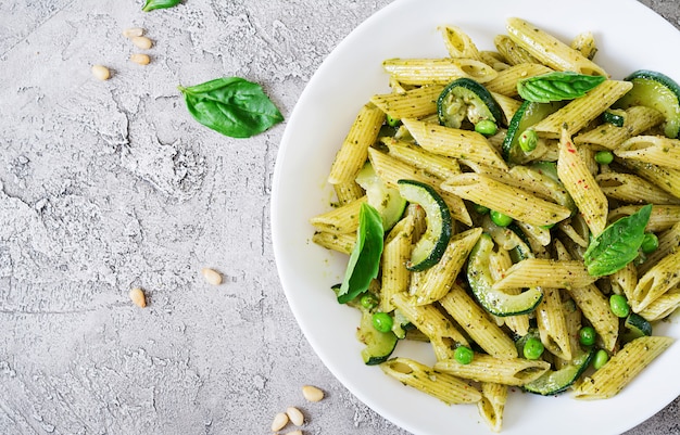 Penne pasta con salsa de pesto, calabacín, guisantes y albahaca. Comida italiana. Vista superior. Endecha plana.