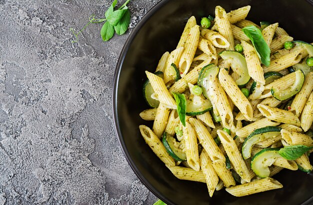 Penne pasta con salsa de pesto, calabacín, guisantes y albahaca. Comida italiana. Vista superior. Endecha plana.