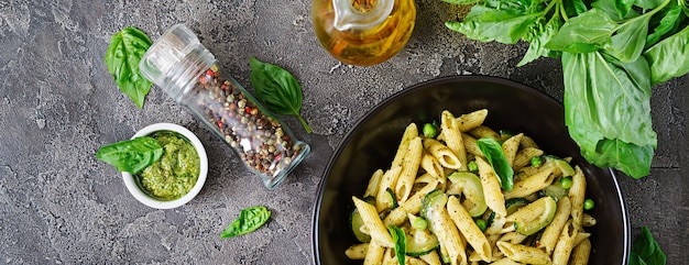 Penne pasta con salsa de pesto, calabacín, guisantes y albahaca. Comida italiana. Vista superior. Endecha plana.