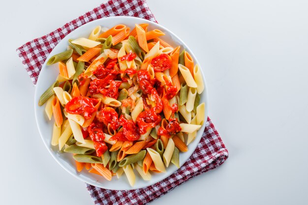 Penne pasta con tomate, salsa en un plato sobre blanco y papel de cocina