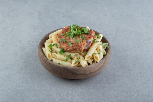 Penne con pollo asado en tazón de madera.