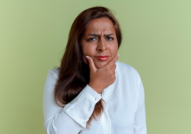 Pensamiento casual mujer de mediana edad caucásica poniendo la mano en el mentón aislado en verde oliva