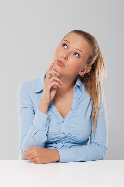 Foto gratuita pensamiento y pensativo mujer sentada en el escritorio blanco