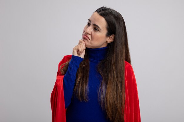 Pensando joven superhéroe mirando a un lado agarró la barbilla aislado sobre fondo blanco.