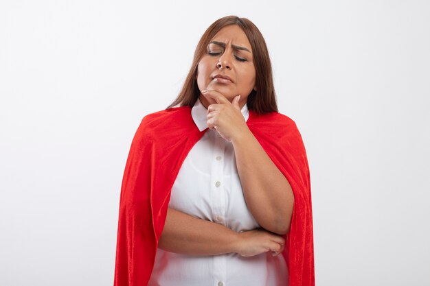 Pensando en la mujer superhéroe de mediana edad con los ojos cerrados agarró la barbilla aislada en blanco