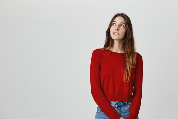 Pensativa joven soñadora, mirando la esquina superior izquierda, imaginando cosas