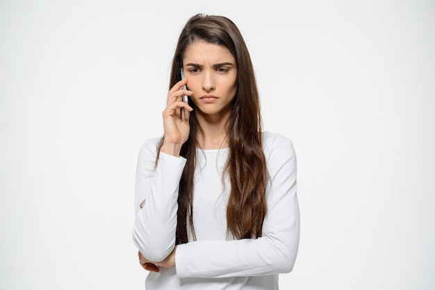 Pensativa, molesta mujer frunciendo el ceño, hablando por teléfono móvil