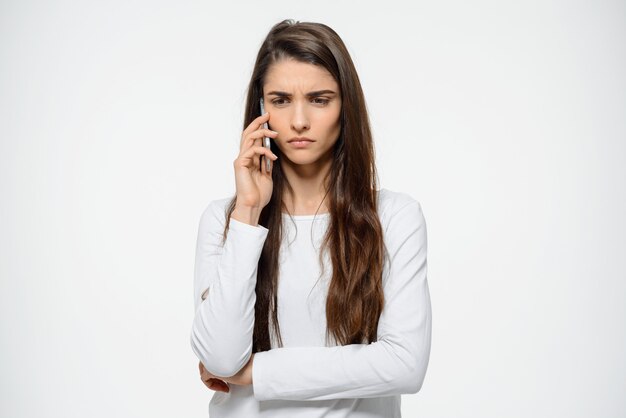 Pensativa, molesta mujer frunciendo el ceño, hablando por teléfono móvil