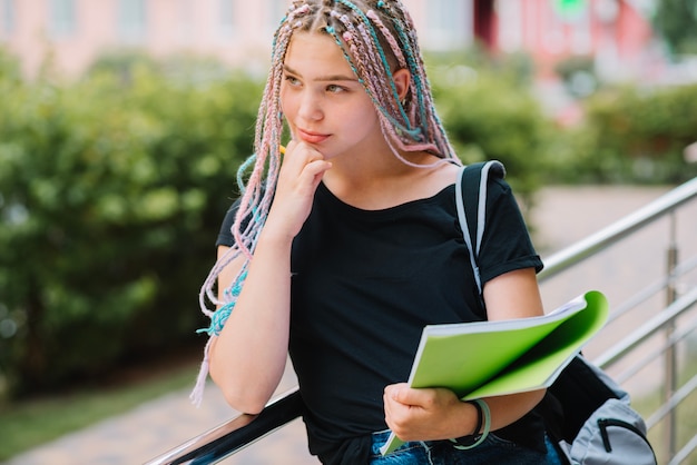 Pensativa niña con el libro de texto