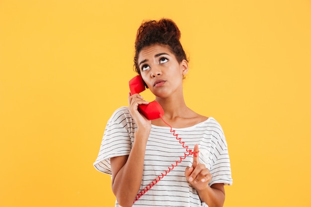 Foto gratuita pensativa pensativa dama hablando por teléfono rojo aislado