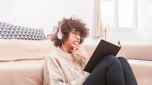 Pensativo adolescente leyendo un libro y escuchando música