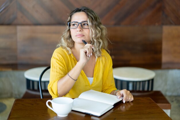 Pensativo creativo freelance tomando notas en el planificador