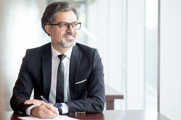 Foto gratuita pensativo hombre de negocios en traje haciendo notas