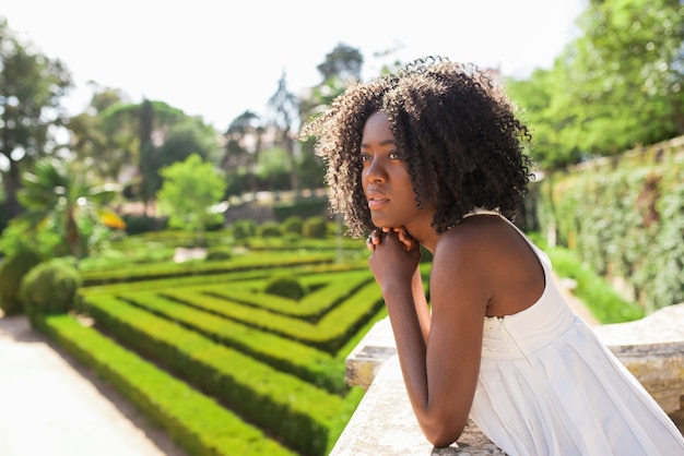 Pensativo joven mujer negra relajante en el parque