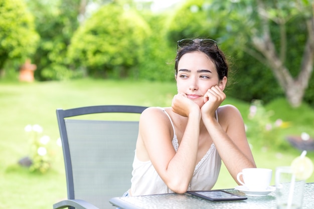 Pensativo joven mujer sentada en el café al aire libre