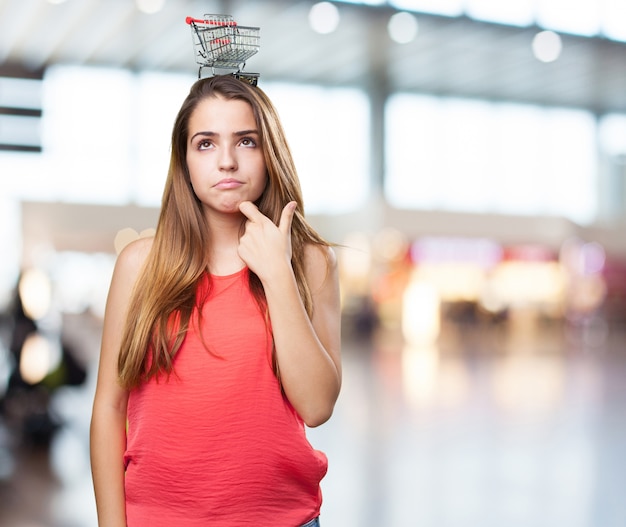 pensativo mujer linda joven que sostiene una cesta de la compra