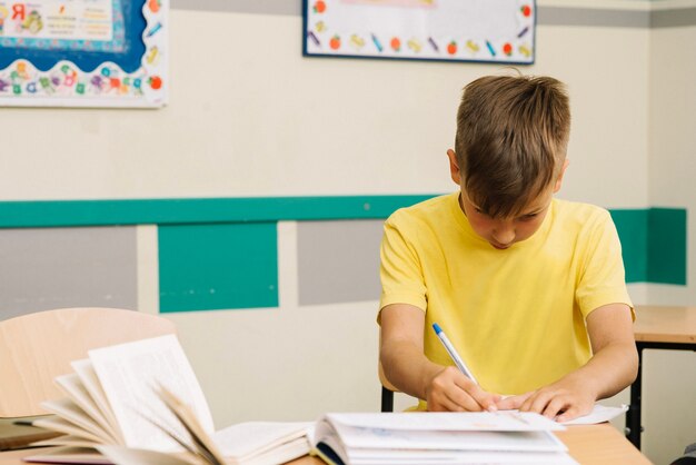 Pensativo niño escribiendo en clase