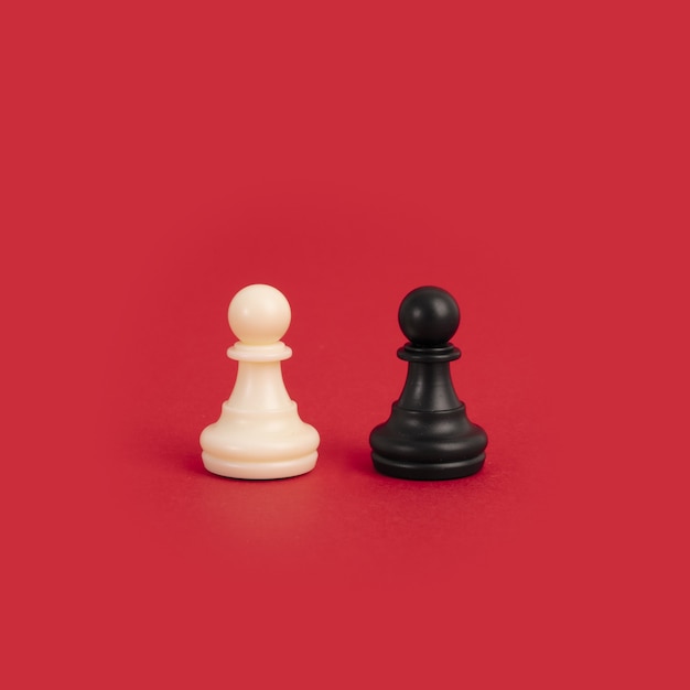 Un peón de ajedrez blanco y negro sobre un fondo rojo brillante, perfecto para conceptos de diversidad