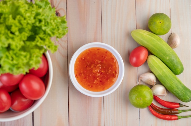 Foto gratuita pepino, limón, tomate, ajo, chile con salsa en el piso de madera.