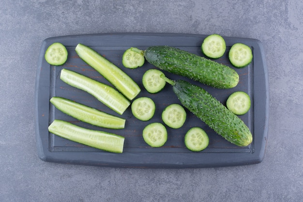 Foto gratuita pepinos verdes picados y en rodajas sobre una tabla de madera