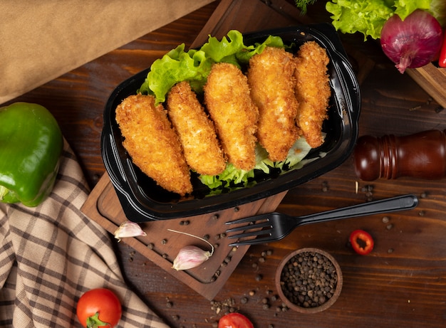 Pepitas de pollo frito estilo KFC para llevar en un recipiente negro