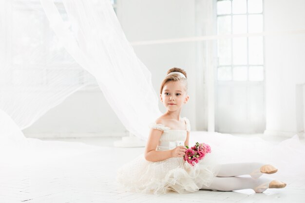 La pequeña bailarina con tutú blanco en clase en la escuela de ballet