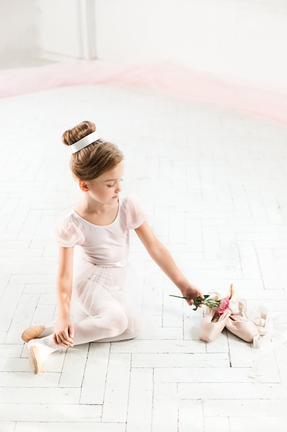 La pequeña bailarina en tutú blanco en clase en la escuela de ballet