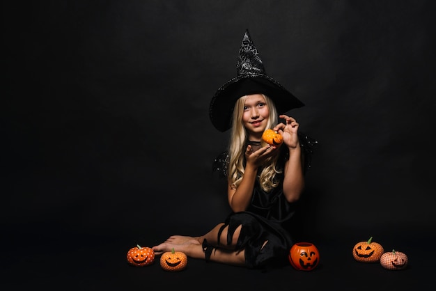 Foto gratuita pequeña bruja descalza mostrando jack-o-lantern