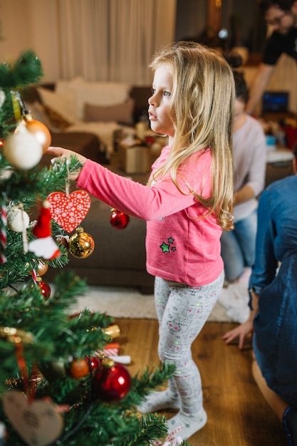 Pequeña chica decorando árbol de navidad