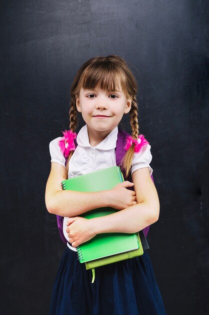 Pequeña colegiala con libros