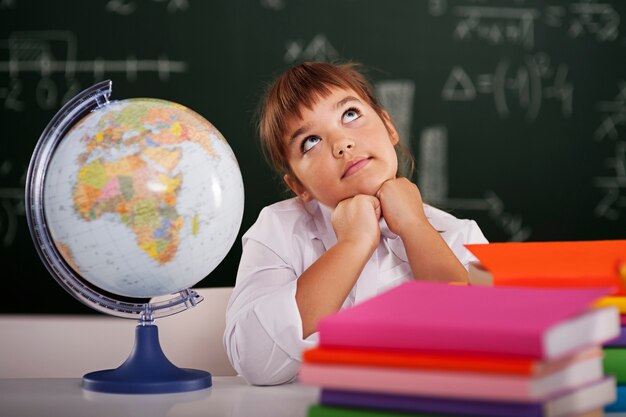 Pequeña colegiala soñando en el aula