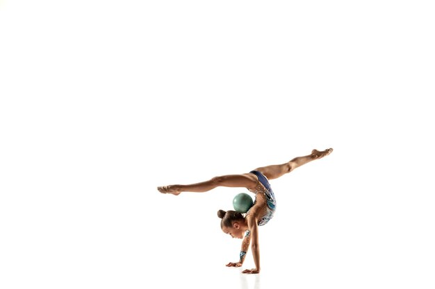 Pequeña gimnasta femenina flexible aislada en la pared blanca