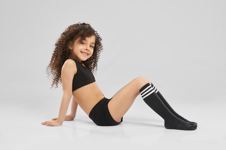 Foto gratuito pequeña gimnasta sentada en el piso del estudio