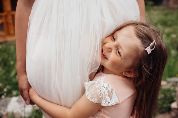 La pequeña hija abraza las piernas de mon