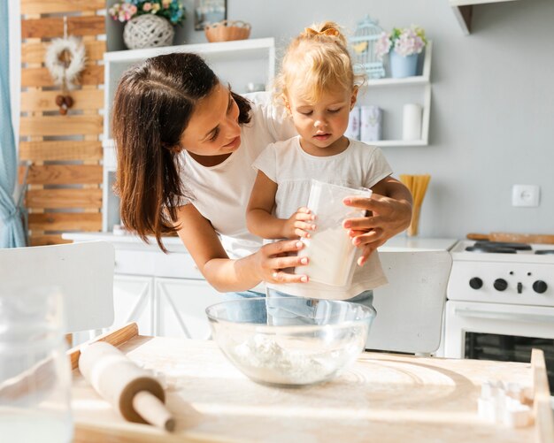 Pequeña hija y madre cocinando juntas