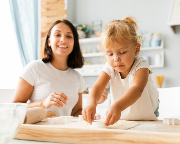 Pequeña hija y madre preparando galletas