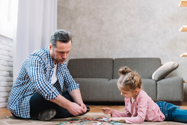 Foto gratuita pequeña hija y padre jugando rompecabezas en casa