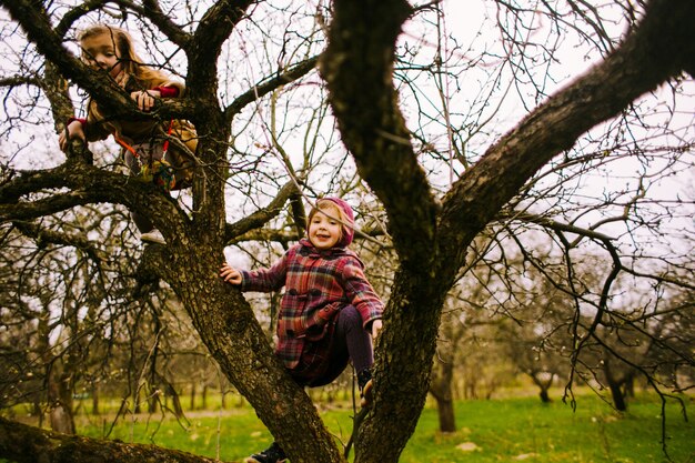 La pequeña hija sentada en el árbol