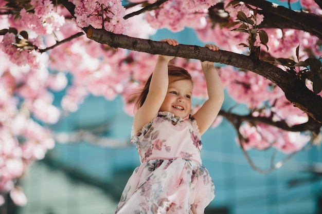 La pequeña hija sostiene una rama del árbol rosado floreciente