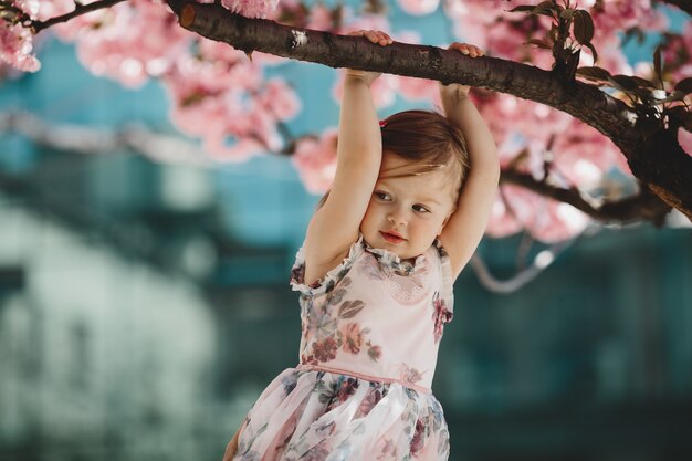 La pequeña hija sostiene una rama del árbol rosado floreciente