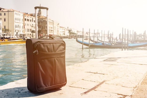 Pequeña maleta sobre fondo urbano de viajes, Venecia, Italia. Horizontal. Viraje. Concepto De Las Vacaciones Del Viaje.