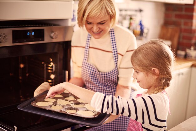 Pequeña niña ayudando a la abuela mientras hornea